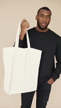 Portrait of a young man holding a blank white tote bag, ideal for mockup and branding purposes.